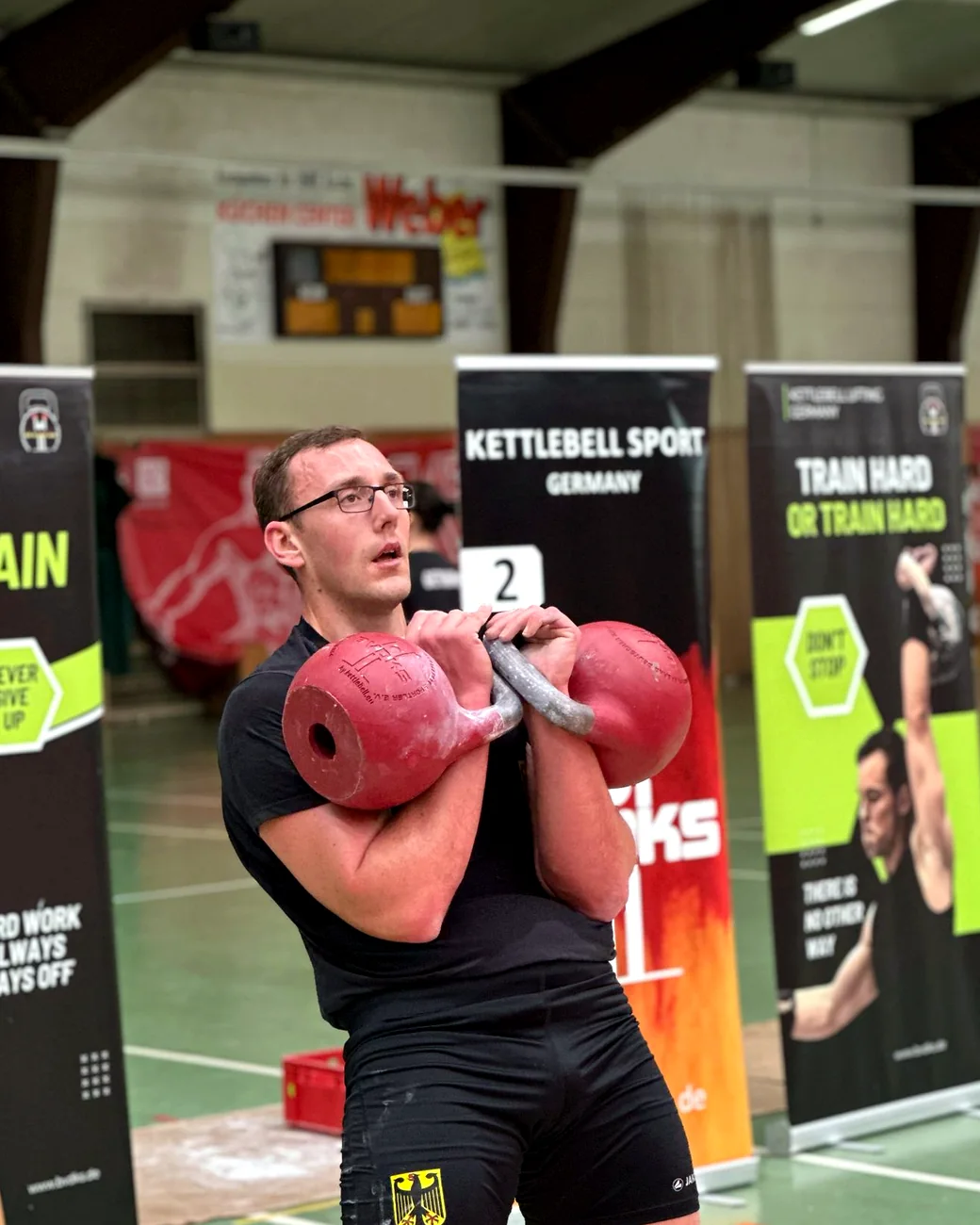Alexander Jäck mit zwei Kettlebells in der Rack-Position während eines Wettkampfs